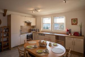 a kitchen with a wooden table with chairs and a table and a table at FEWO Maisonettenwohnung in Steinkirchen