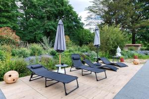 a group of chairs and umbrellas on a patio at Gite Douceur de vivre in Saint-Avaugourd-des-Landes