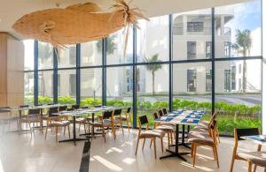 a dining room with tables and chairs and windows at Arena jakovi condotel in Cam Lâm