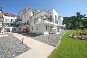 a large white building with a walkway in a yard at Haus Meeresblick A 2 12 BLU in Baabe