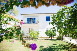 ein weißes Haus mit blauen Fenstern und Blumen in der Unterkunft Morosini Apartments in Biograd na Moru