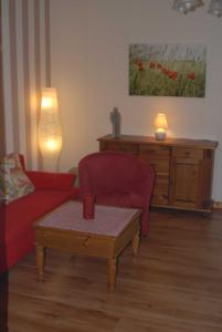 a living room with a red couch and a coffee table at Ferienwohnung Nachbars Garten in Grünendeich +26 photos