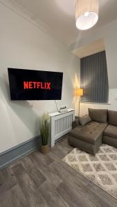 a living room with a couch and a netflix sign on the wall at Sheffield city centre apartment in Midland