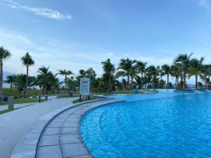 a swimming pool with palm trees in a resort at Arena jakovi condotel in Cam Lâm