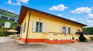 a yellow and red house with a table and an umbrella at Villa Natina in Pizzo