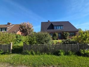 a house with a wooden fence in the yard at Hook in Midlum