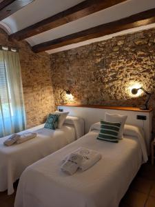 two beds in a room with a stone wall at Mas Palou in Pla del Panadés +70 photos