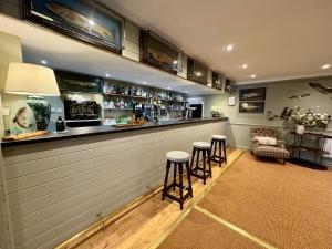 Eine Bar mit Hockern in einem Raum mit einer Theke in der Unterkunft Scourie Hotel in Scourie