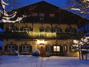 a house decorated with christmas lights in the snow at Landhaus SeenSucht in Schliersee