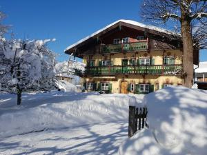 a building with a snow covered yard in front of it at Landhaus SeenSucht in Schliersee