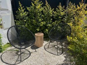 two black chairs and a stump next to some bushes at Casa Alegria in Oeiras