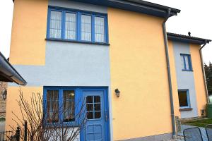a yellow and blue house with a blue door at Grischow Ferienwohnung in Grischow