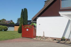 a red and white garage with a red gate at Thiessen - Ferienwohnung mit sonnigem Balkon in Silberstedt