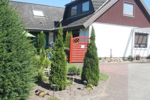 a house with a red door and some trees at Thiessen - Ferienwohnung mit sonnigem Balkon in Silberstedt