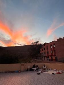 a group of people sitting on a wall at sunset at Jnan Narjiss atlas in Asni