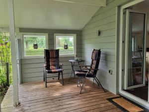 a porch with two chairs and a table and two windows at Ferienhaus Paulsen - gemütliches Häuschen mit vollständig eingezäuntem Garten und Kamin in Silberstedt