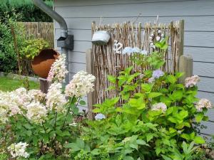 a garden with flowers next to a wooden fence at Ferienhaus Paulsen - gemütliches Häuschen mit vollständig eingezäuntem Garten und Kamin in Silberstedt