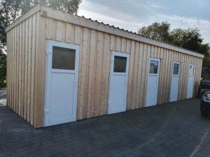 a large wooden building with four doors on it at Ferien am Idasee 85041 in Ostrhauderfehn