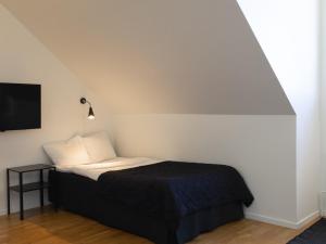 a bed with a black blanket and a white wall at Hotel Torslanda in Torslanda