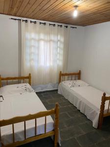 two beds in a room with a window at Quinta da Ana, Casa de Roça in Baependi