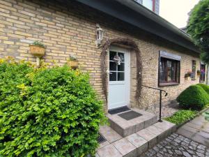 a brick house with a white door and some bushes at Ferienwohnung Hinz - Gemütliche Unterkunft für 2 Personen mit modernem Bad in Ellingstedt