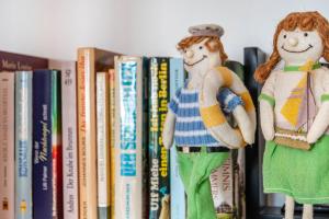 two dolls are sitting on books on a shelf at Apartment Korthals 42 in Wangerland