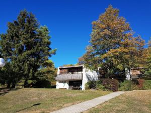a building in a park with two trees and a sidewalk at Berg-Bungalows Leinleitertal in Heiligenstadt +58 photos