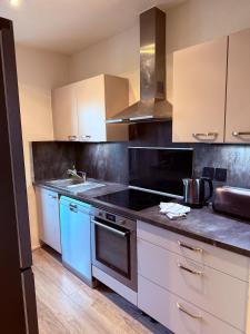 a kitchen with white cabinets and blue appliances at T3 spacieux - Centre et Technhom in Belfort +21 photos