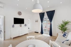 a white living room with a tv and a couch at Casa Vacanza Sunshine in Meta