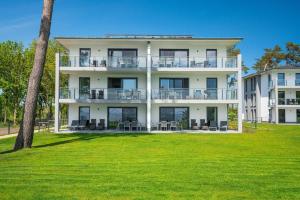 a large white building with a lawn in front of it at Appartement "Opal" mit Penthouseflair - Oase am Haff in Garz