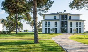 a white house with trees in front of it at Appartement "Opal" mit Penthouseflair - Oase am Haff in Garz
