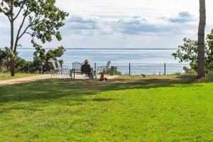 a person sitting on a bench next to the ocean at Appartement "Opal" mit Penthouseflair - Oase am Haff in Garz +45 photos