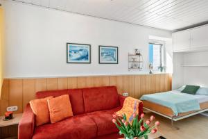 a living room with a red couch and a bed at Apartment Korthals 41 in Wangerland