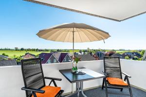 a table and two chairs with an umbrella on a balcony at Apartment Korthals 41 in Wangerland +12 photos