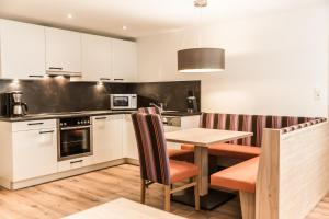 een keuken met witte kasten en een houten tafel en stoelen bij A Casa Smaragd Appartements in Sölden