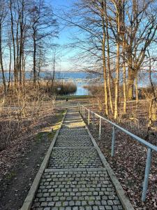 a stone path with a fence and a body of water at Ferien_HAUS SEEOASE in Göhren-Lebbin