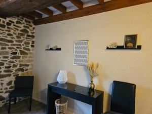 a room with a desk and two chairs and a stone wall at Le relai de la tannerie in Lanvallay