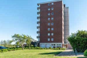a tall red brick building next to a grass field at Apartment Korthals 41 in Wangerland