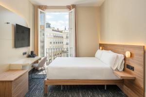 a bedroom with a bed and a desk and a window at FORTINN Puerta del Sol in Madrid