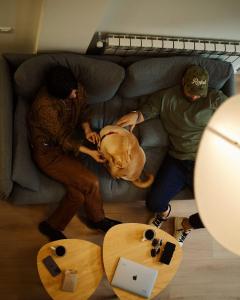 two people and a dog laying on a couch at Artifact Apart Hotel in Tbilisi City