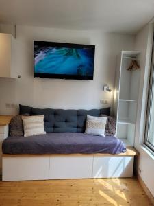 a room with a couch with a tv on the wall at Avec CLIMATISEUR appartement DESIGN vous propose, un appartement 2 chambres et salon, 3 appartements une pièce, NETFLIX, lits faits à votre arrivée, serviettes de toilette, Ménage, Wifi ,Plage à 190m, BOX à Vélos, paiement 3 fois sans frais in Dieppe