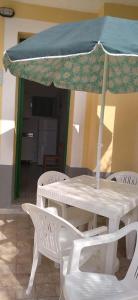 a white table and chairs with a blue umbrella at B&B Josefine in Marina di Camerota