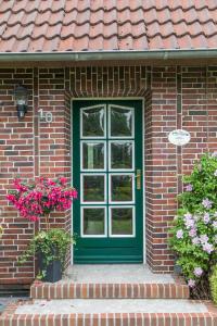 a green door on a brick house with flowers at Birgits Huuske in Stedesdorf