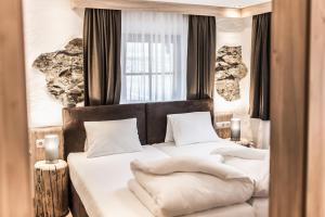 1 dormitorio con 2 camas con sábanas y almohadas blancas en A Casa Smaragd Appartements, en Sölden
