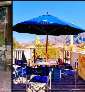 a table and chairs under an umbrella on a deck at Cafayate Backpackers in Cafayate