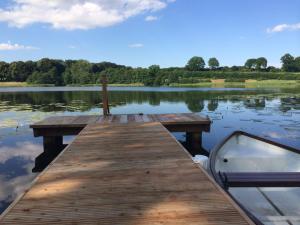 a wooden dock with a boat on a lake at Ferienhaeuser Poenitz am See in Klingberg