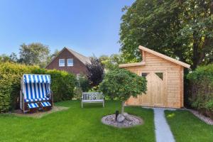 a garden with a bench and a wooden shed at Ferienhaeuser Deichkrone in Bensersiel