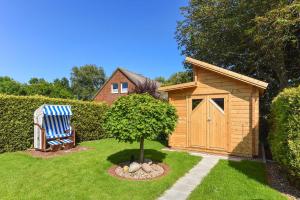 a wooden shed with a chair next to a tree at Ferienhaeuser Deichkrone in Bensersiel