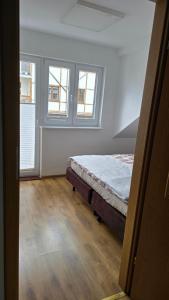 a bedroom with a bed and two windows at Apartament Riva in Rowy