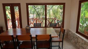 a wooden table and chairs in a room with windows at Casa Mayali - Walk to Lagoon in Bacalar